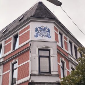 Das Wappen von Bremerhaven Lehe ist oben an einer Hauswand in Lehe über einem Fenster sichtbar.