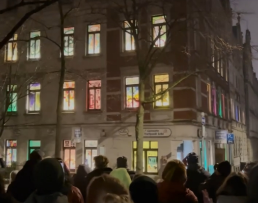 Ein beleuchtetes Haus mit vielen Menschen davor